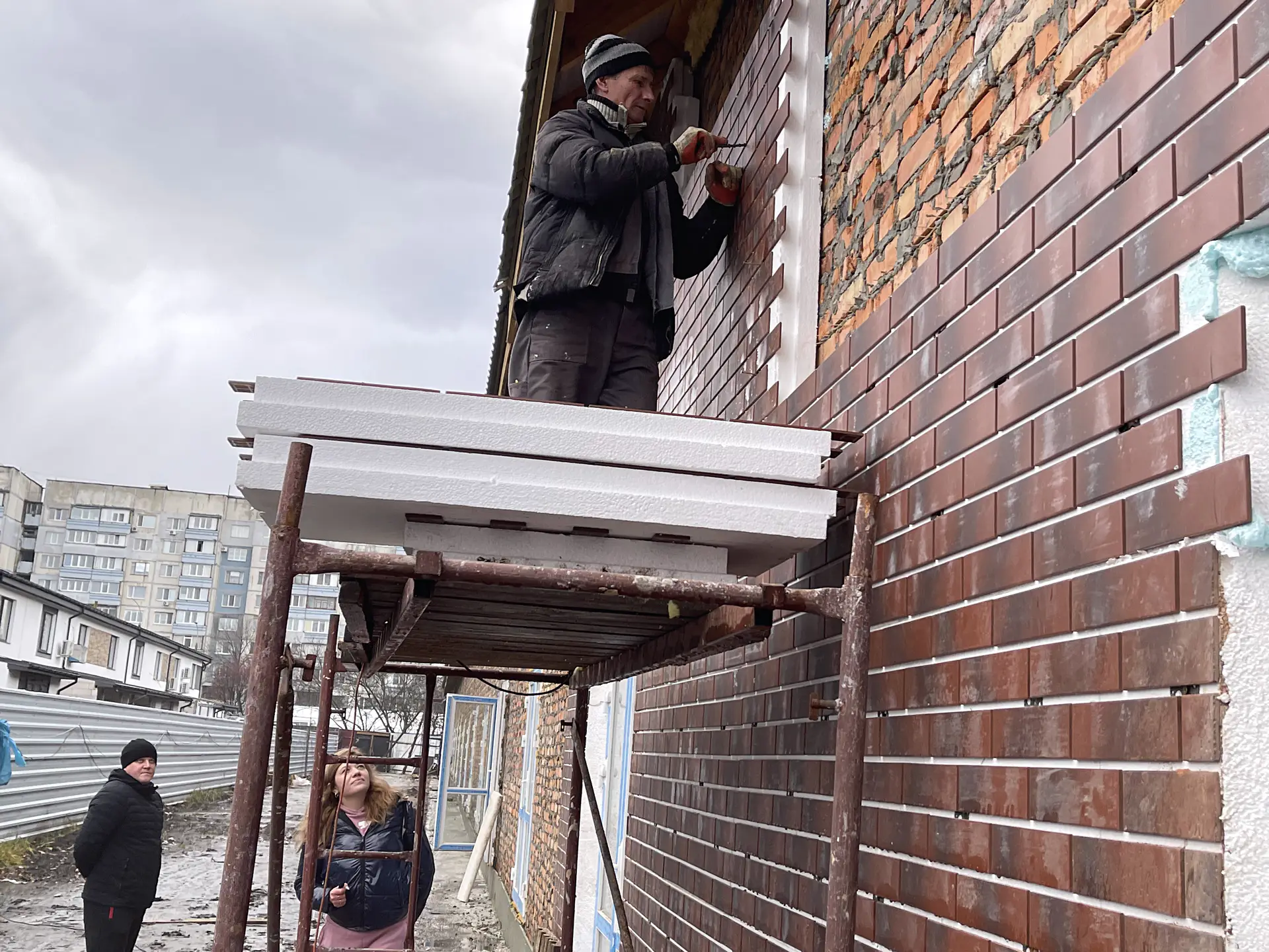 Workers mounting Royal Facade panels during winter construction season
